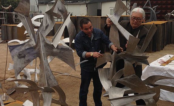 Baet (right) makes the final adjustments to the sculpture at the metal foundry in China.